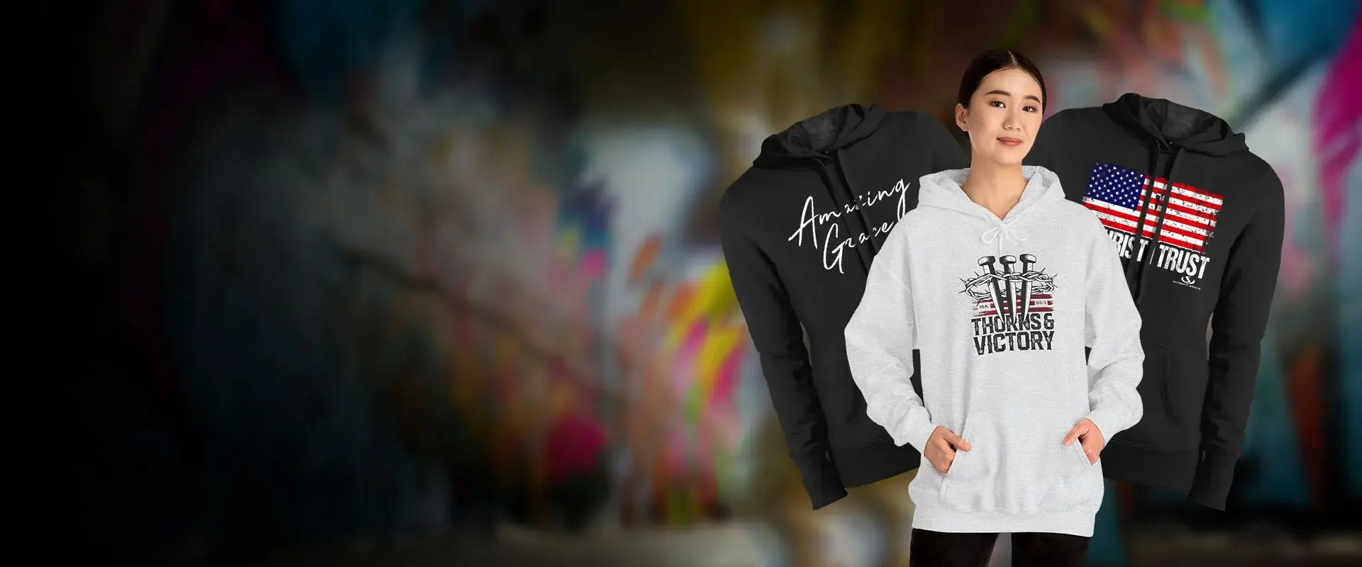 Woman wearing a gray hoodie with motivational text, flanked by two other hoodies with different designs.